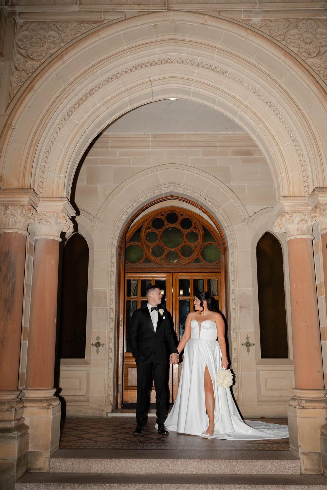 Bride and groom arriving at a stone archway venue