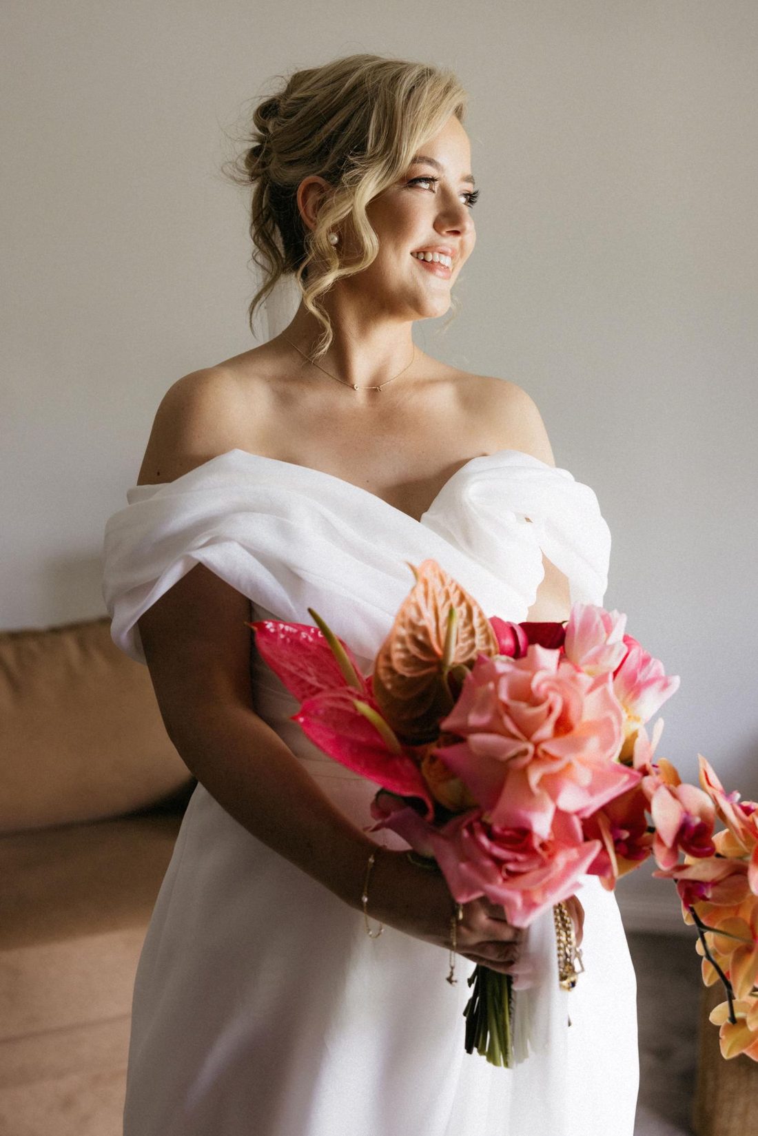 Bride holding a vibrant bouquet, off-shoulder gown