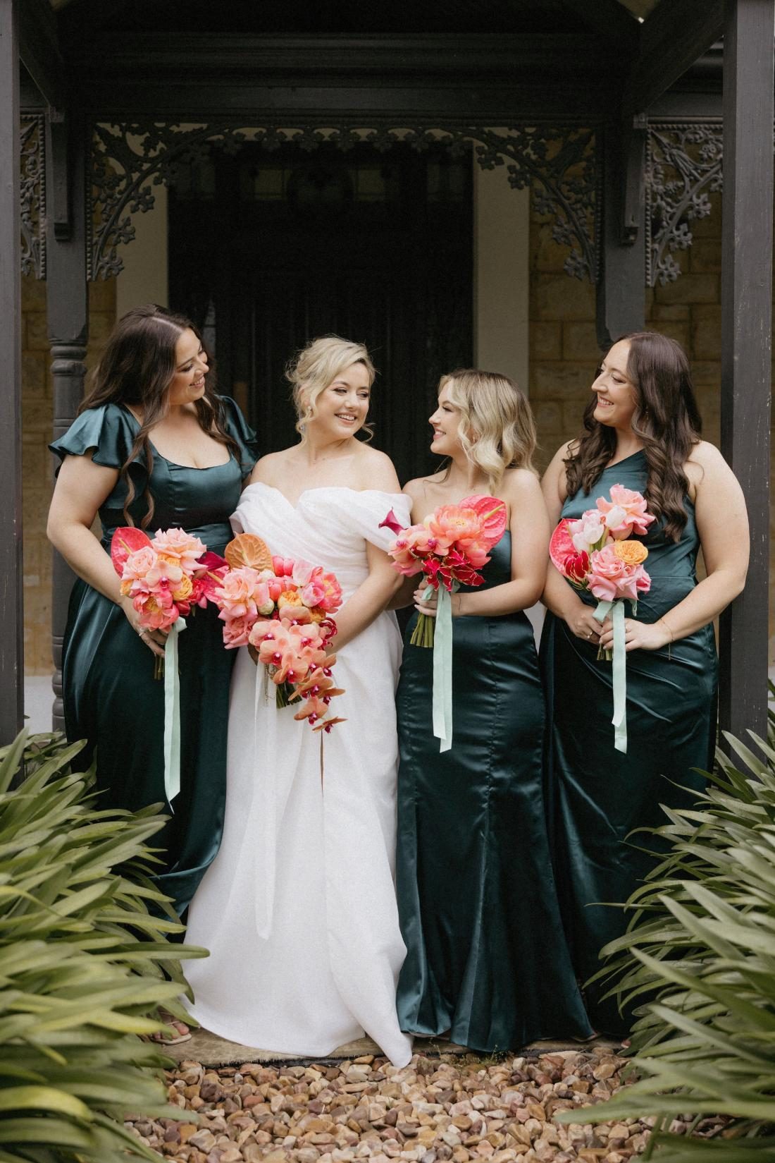 Bridesmaids in emerald gowns at a venue entrance