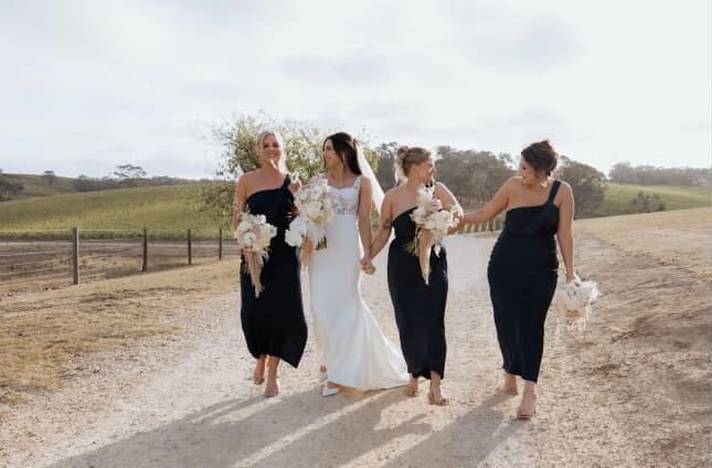 Bridesmaids walking a forest road in deep green gowns