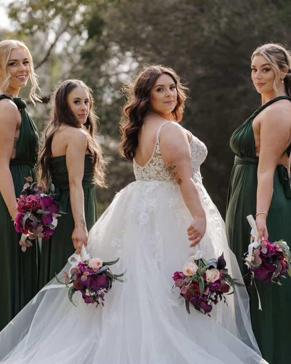 Bridesmaids in emerald gowns in a garden