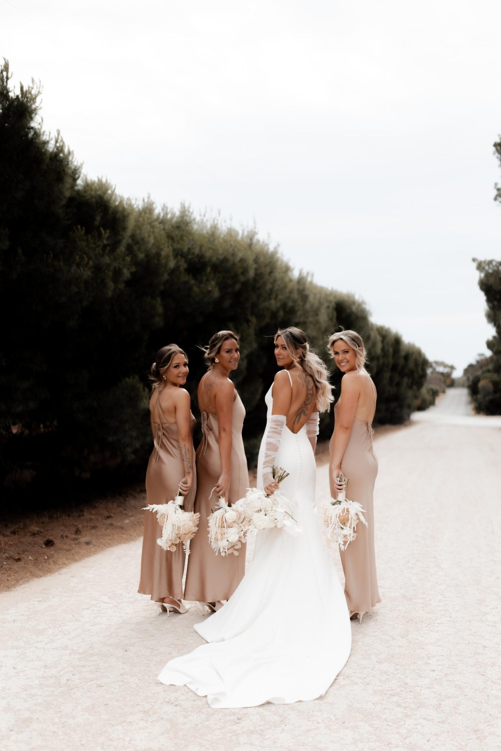 Bridal party walking a country road, bride looking back over her shoulder